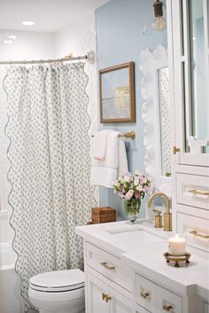 a white toilet sitting next to a bath tub under a bathroom mirror and shower curtain