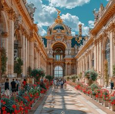 an ornate building with red flowers in the foreground and people walking through it on a sunny day