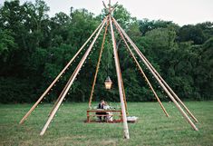 a man and woman sitting at a table in front of a teepee with lights on it