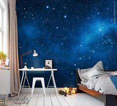 a bedroom with a bed and desk in front of a starry sky wall mural