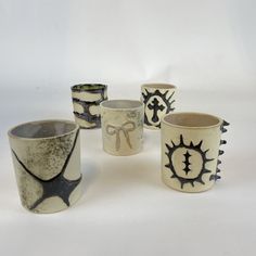 five ceramic cups with designs on them sitting next to each other in front of a white background