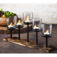 four tealight candles are sitting on a wooden stand