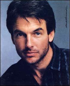 a close up of a person wearing a black shirt and looking at the camera with a serious look on his face