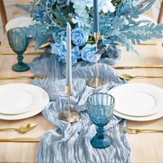 the table is set with blue flowers and candles