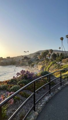 the sun is setting over the beach with palm trees and flowers on either side of the road