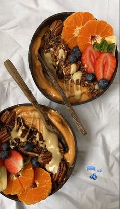 two bowls filled with fruit and nuts on top of a white sheet covered tablecloth