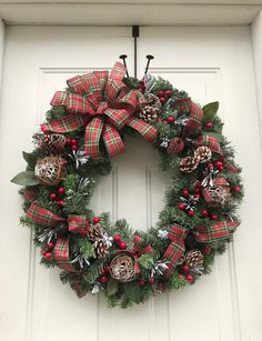 a christmas wreath on the front door with pine cones, holly and bells hanging from it