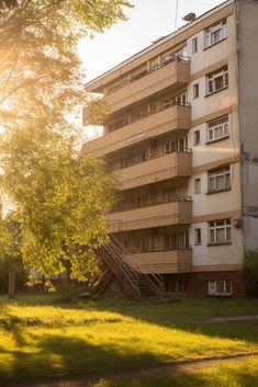 an apartment building with stairs leading up to the second floor and trees in front of it