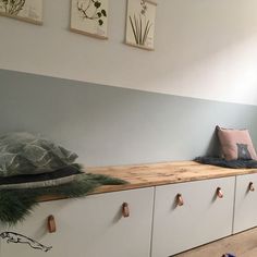 a room that has some drawers on the wall and two pictures above it with plants