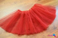 a red tulle skirt sitting on top of a wooden floor