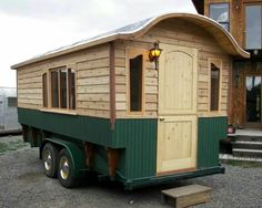 a green and white tiny house sitting on the back of a truck