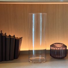 a glass vase sitting on top of a table next to books and a candle holder