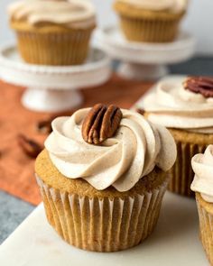 three cupcakes with frosting and pecans on top sitting on a table