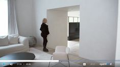 a woman standing in a living room next to a white couch