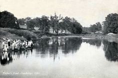 an old black and white photo of people standing on the edge of a river