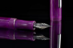 a purple fountain pen sitting on top of a reflective surface