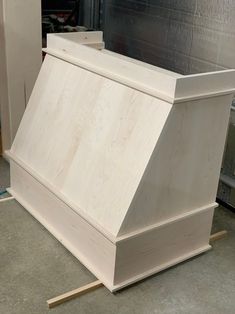 a white wooden box sitting on top of a floor next to a piece of plywood