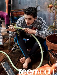 a young man is sitting on the floor holding a hose