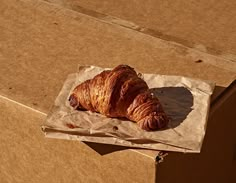 a croissant sitting on top of a piece of paper in a cardboard box