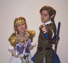 two people dressed up in costumes standing next to each other holding swords and pointing at the camera