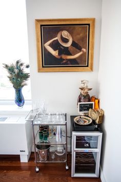 there is a painting on the wall next to a shelf with glasses and other items