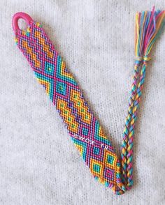 a colorful beaded object laying on top of a white blanket next to a tassel