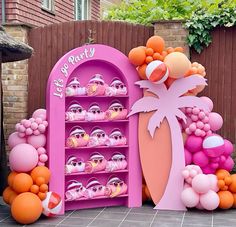 a pink and orange display case filled with lots of balloons in the shape of palm trees