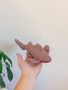 a hand is holding a small toy airplane in front of a potted green plant