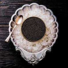 a bowl filled with lots of white and black stuff next to a spoon on top of a wooden table