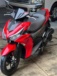 a red and black motorcycle parked next to a car