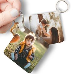 a person holding up two square photo keychains with the same image on them