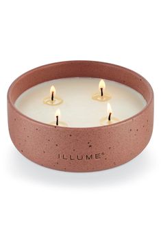 three lit candles in a terracotta bowl with the word illume written on it