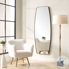 a living room with a chair, mirror and lamp