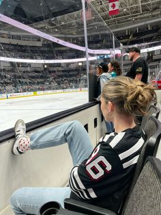 a woman sitting in a chair at an ice hockey rink with her feet on the bench