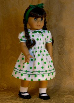 a doll wearing a green and white dress with polka dots on it's chest