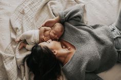 a woman laying on top of a bed holding a baby