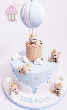 a blue and white cake with teddy bears in a hot air balloon on it's top