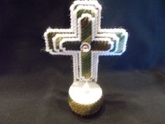 a crocheted cross is displayed on a black tablecloth with white and green stripes