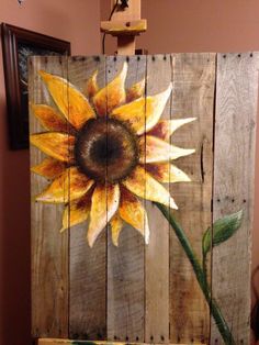 an image of a sunflower painted on wood planks with the words pin it