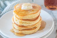 a stack of pancakes on a plate with butter and syrup drizzled on top