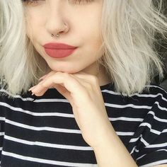 a close up of a person wearing a black and white striped shirt with red lipstick