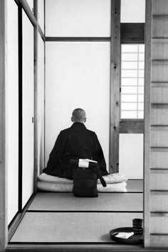 a man sitting on top of a floor next to a table filled with books and papers