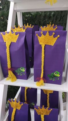 purple bags with yellow decorations on them are sitting in front of a white shelf and some trees