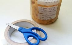 a pair of blue scissors sitting next to a jar of peanut butter on a table