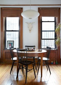 a dining room table with four chairs and a cow head on the wall above it