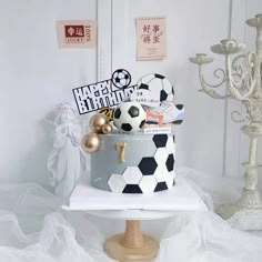 a birthday cake is decorated with soccer balls and other sports related items on a stand