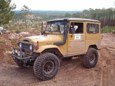 a yellow jeep driving down a dirt road