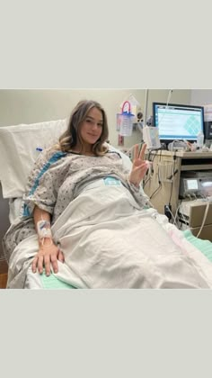 a woman in a hospital bed giving the peace sign