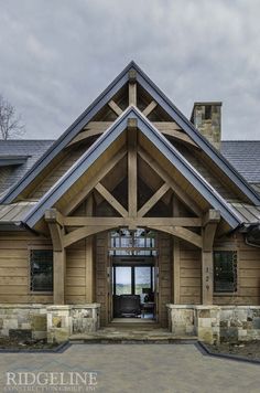 the front entrance to a large home with stone and wood accents on it's exterior