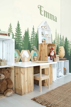 a child's playroom with wooden furniture and trees painted on the wall behind it